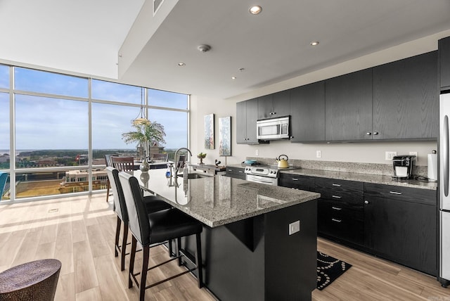 300 E Third # 1302, Little Rock, AR 72201 - kitchen featuring dark cabinets, a sink, stainless steel appliances, a breakfast bar, and a wall of windows