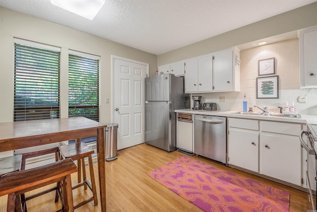451 Forrest Dr, Heber Springs, AR 72543 - kitchen featuring appliances with stainless steel finishes, light countertops, white cabinetry, light wood finished floors, and a sink