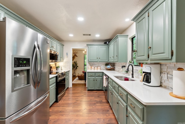 5623 Ridgeway Dr, Benton, AR 72019 - kitchen featuring stainless steel appliances, a sink, decorative backsplash, dark wood-type flooring, and light countertops