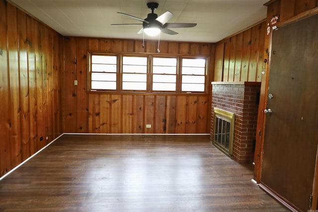 unfurnished living room with a ceiling fan, wood finished floors, a fireplace, and wood walls