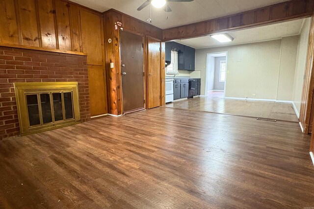 unfurnished living room with a ceiling fan, wood finished floors, baseboards, and a fireplace