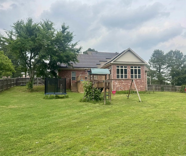 back of house featuring a trampoline, a playground, and brick siding