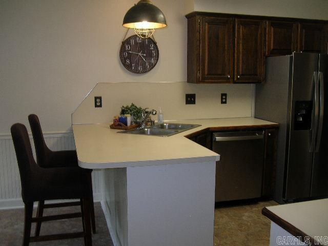11 Sharondale Ct, Maumelle, AR 72113 - kitchen featuring stainless steel appliances, a sink, dark brown cabinets, light countertops, and a peninsula