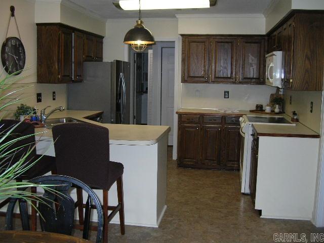 11 Sharondale Ct, Maumelle, AR 72113 - kitchen featuring white appliances, crown molding, dark brown cabinets, light countertops, and a sink
