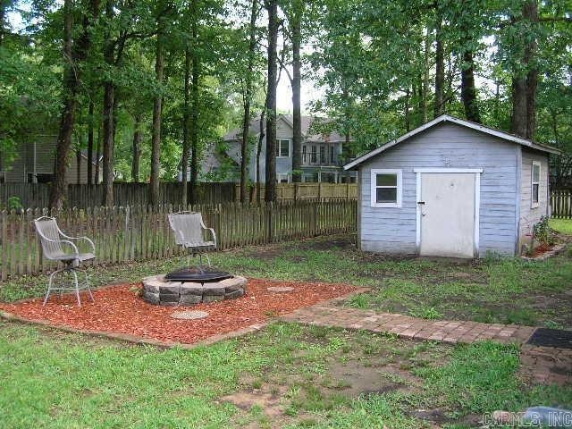11 Sharondale Ct, Maumelle, AR 72113 - view of yard featuring a fire pit, a storage unit, fence, and an outdoor structure