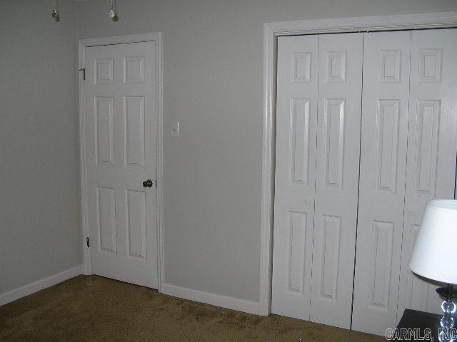 11 Sharondale Ct, Maumelle, AR 72113 - unfurnished bedroom with dark carpet, baseboards, and a closet
