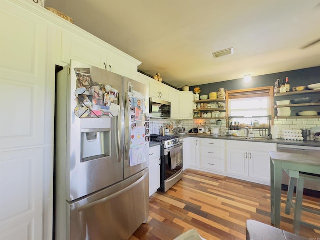 482 Ash Trl, Melbourne, AR 72556 - kitchen featuring stainless steel appliances, open shelves, backsplash, dark countertops, and light wood-style floors