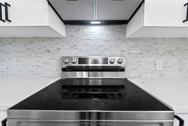 3113 W 11th, Little Rock, AR 72204 - kitchen view of stainless steel electric range oven, decorative backsplash, white cabinetry, and light stone countertops