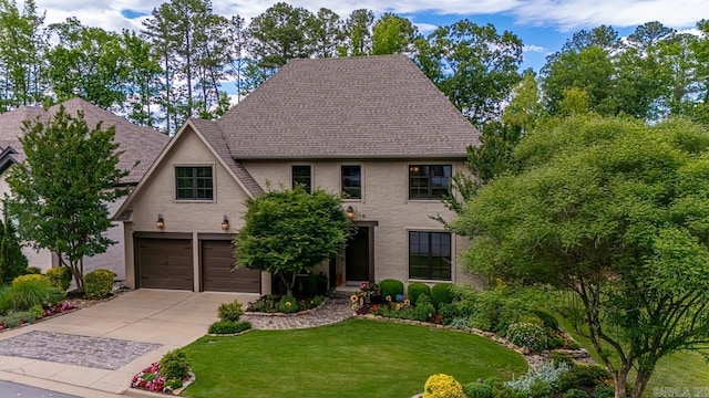145 Cove Creek Ct, Little Rock, AR 72211 - tudor home featuring an attached garage, driveway, a front yard, and roof with shingles