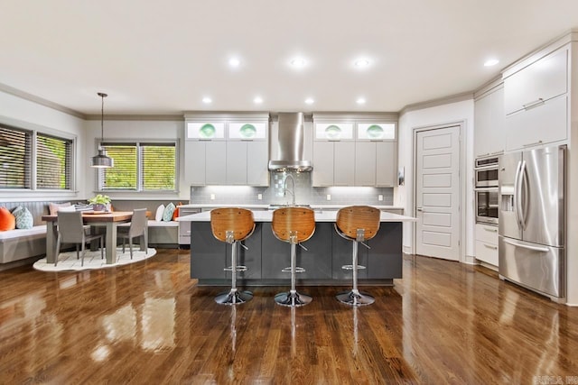 145 Cove Creek Ct, Little Rock, AR 72211 - kitchen with stainless steel appliances, wall chimney exhaust hood, light countertops, a center island with sink, and crown molding