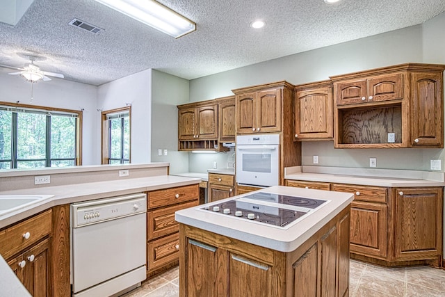 16 Zutano Ln, Hot Springs Village, AR 71909 - kitchen with white appliances, ceiling fan, a textured ceiling, brown cabinetry, and a center island