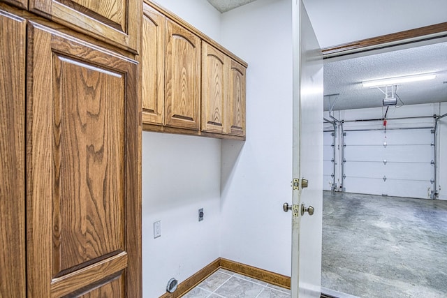 16 Zutano Ln, Hot Springs Village, AR 71909 - clothes washing area with a garage, cabinet space, a textured ceiling, electric dryer hookup, and baseboards