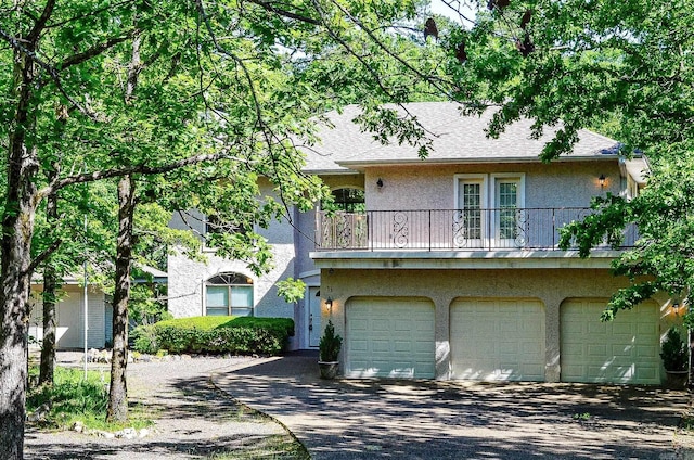 16 Zutano Ln, Hot Springs Village, AR 71909 - view of front facade with stucco siding, driveway, an attached garage, and a balcony