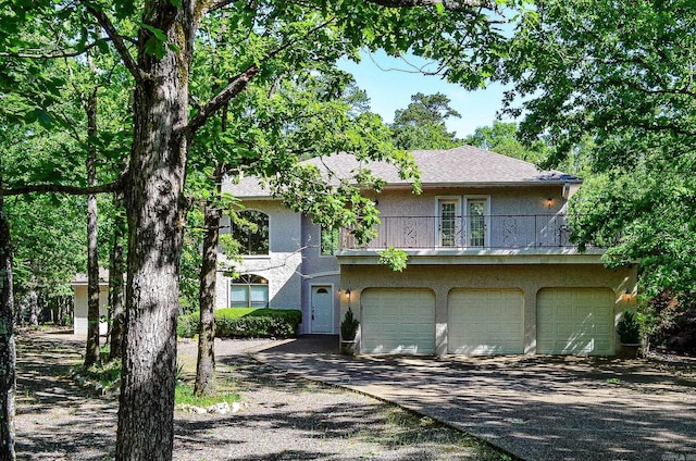 16 Zutano Ln, Hot Springs Village, AR 71909 - view of front facade with stucco siding, a balcony, driveway, and an attached garage