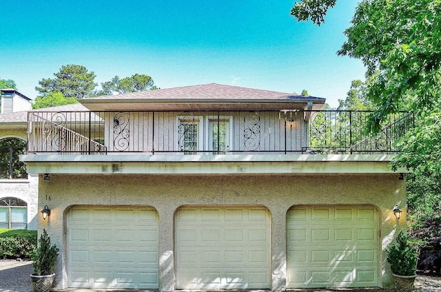 16 Zutano Ln, Hot Springs Village, AR 71909 - rear view of house with an attached garage, a balcony, board and batten siding, and roof with shingles