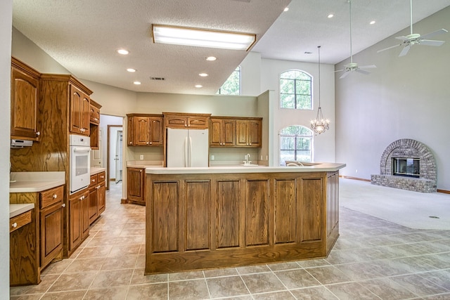 16 Zutano Ln, Hot Springs Village, AR 71909 - kitchen featuring white appliances, high vaulted ceiling, a spacious island, light countertops, and a brick fireplace