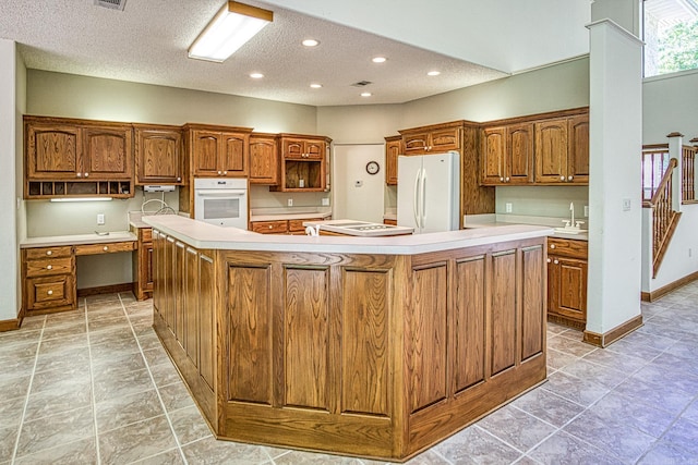 16 Zutano Ln, Hot Springs Village, AR 71909 - kitchen with white appliances, a large island, brown cabinets, open shelves, and a textured ceiling