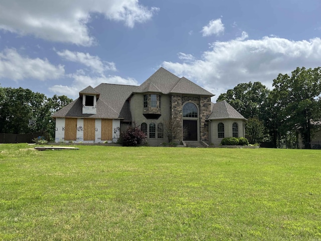 french provincial home with a front lawn, stone siding, and roof with shingles