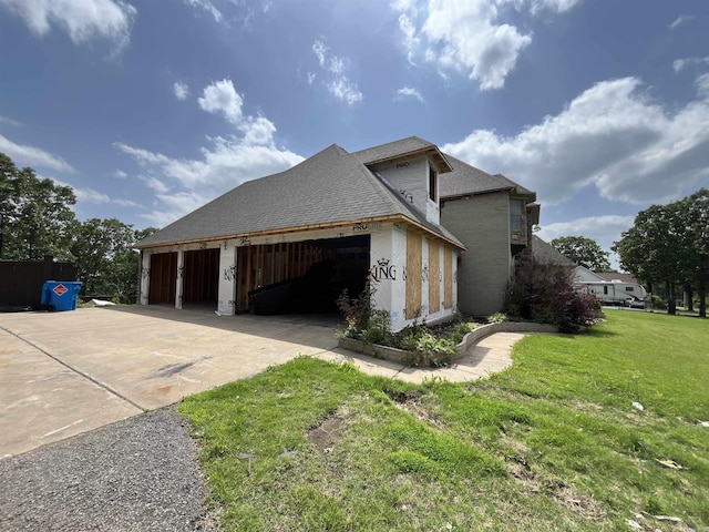 view of side of property featuring driveway, a yard, a garage, and a shingled roof
