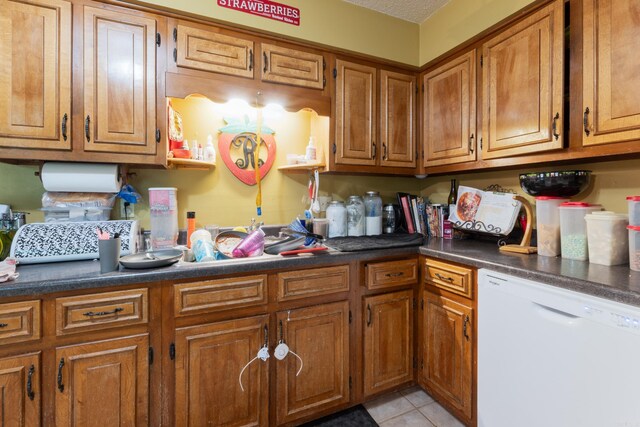7104 Foxrun E End Dr, Mabelvale, AR 72103 - kitchen featuring white dishwasher, brown cabinets, light tile patterned floors, and dark countertops