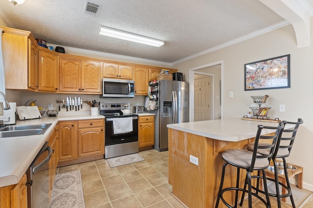kitchen with stainless steel appliances, a sink, a breakfast bar, light countertops, and crown molding