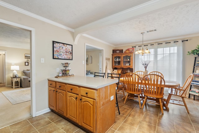 kitchen with a textured ceiling, a chandelier, light countertops, ornamental molding, and decorative light fixtures