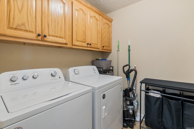 laundry area with independent washer and dryer, cabinet space, and a textured ceiling