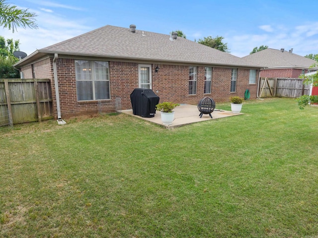back of house featuring a patio area, brick siding, roof with shingles, and an outdoor fire pit