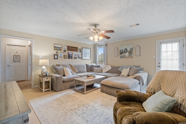 living area with a ceiling fan, plenty of natural light, ornamental molding, a textured ceiling, and light colored carpet