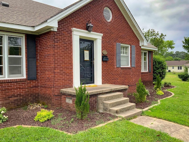 1400 Tulip Ave, Searcy, AR 72143 - view of exterior entry with brick siding, a shingled roof, and a yard