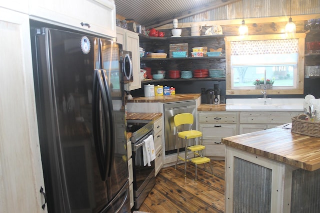 kitchen featuring freestanding refrigerator, wood counters, electric stove, stainless steel dishwasher, and dark wood finished floors