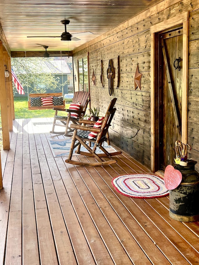 wooden deck featuring covered porch and a ceiling fan