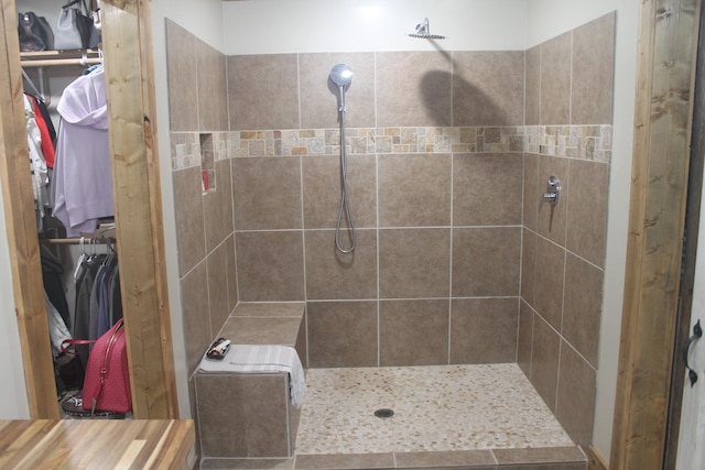 full bathroom featuring a tile shower and a spacious closet
