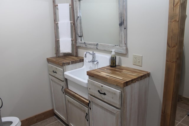bathroom with tile patterned flooring, baseboards, a sink, and toilet