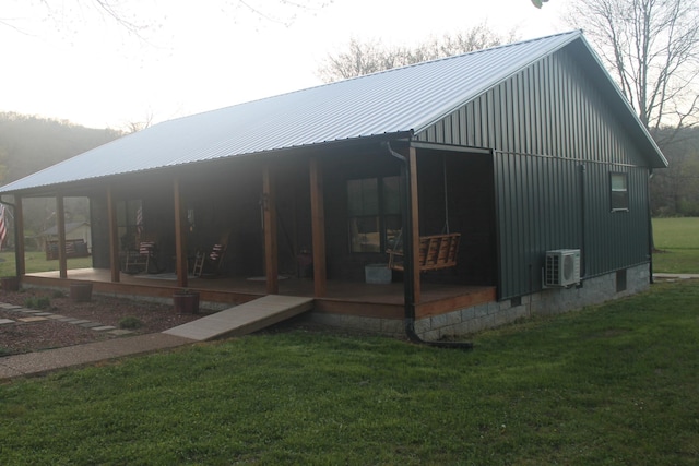 back of property with ac unit, a yard, and metal roof
