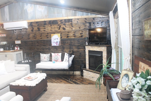 living room with a wall unit AC, wood finished floors, wood walls, and a stone fireplace