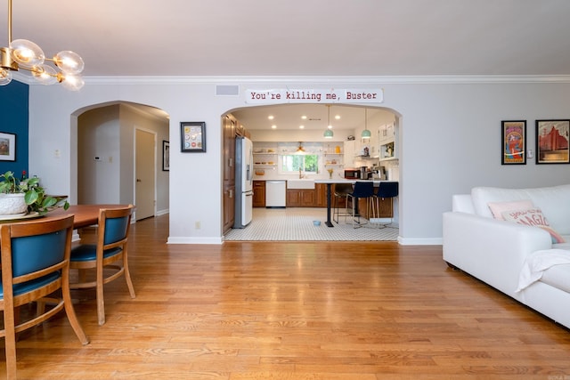 375 Goshen Ave, North Little Rock, AR 72116 - living room featuring arched walkways, light wood-style floors, ornamental molding, baseboards, and a chandelier