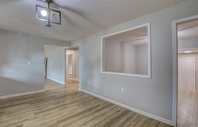 empty room with wood finished floors, baseboards, and a textured ceiling
