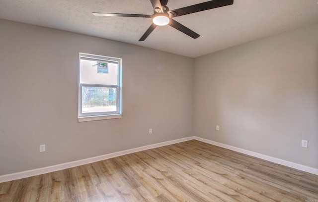 spare room with light wood-style flooring, baseboards, ceiling fan, and a textured ceiling