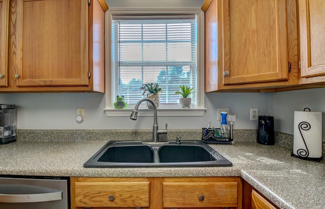kitchen with a sink, stainless steel dishwasher, plenty of natural light, and brown cabinetry
