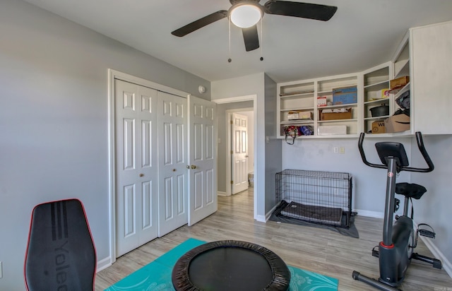exercise room with a ceiling fan, wood finished floors, and baseboards