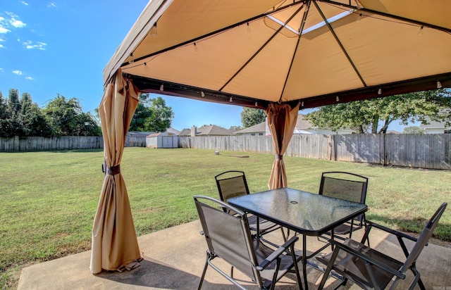 view of patio / terrace featuring a gazebo, outdoor dining space, a storage unit, and an outdoor structure