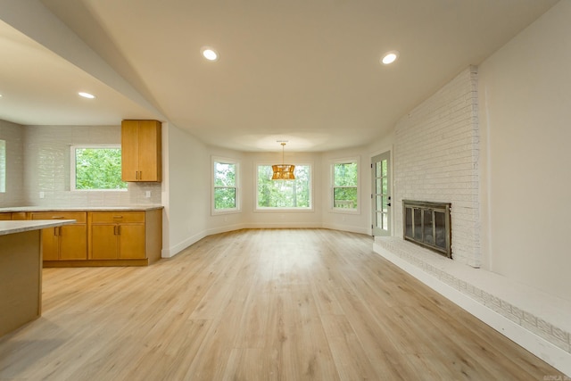 9008 Leatrice Dr, Little Rock, AR 72227 - unfurnished living room with healthy amount of natural light, light wood-style flooring, a brick fireplace, recessed lighting, and baseboards