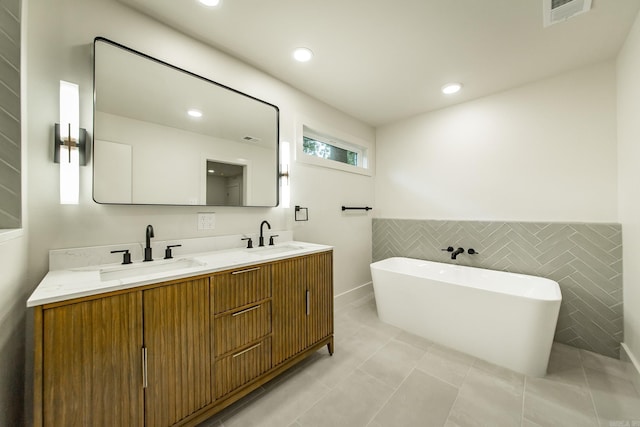 9008 Leatrice Dr, Little Rock, AR 72227 - full bathroom featuring a freestanding bath, double vanity, tile walls, recessed lighting, and a wainscoted wall