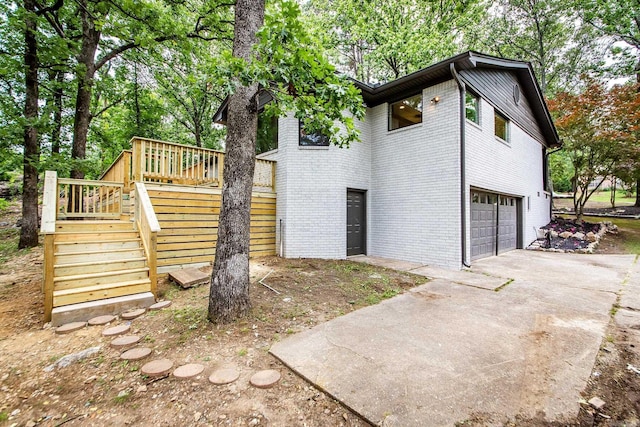 9008 Leatrice Dr, Little Rock, AR 72227 - view of side of home featuring stairway, an attached garage, driveway, brick siding, and a wooden deck