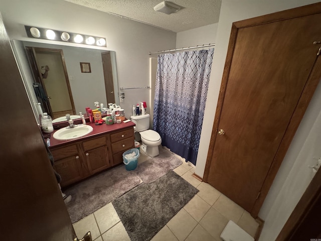 bathroom featuring toilet, a textured ceiling, vanity, tile patterned flooring, and curtained shower