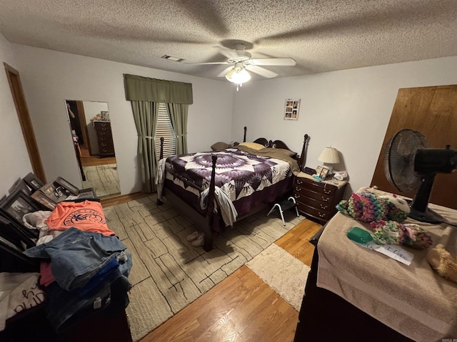 bedroom with light wood finished floors, a textured ceiling, and a ceiling fan