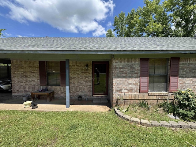 view of front of house with roof with shingles, a front lawn, and brick siding