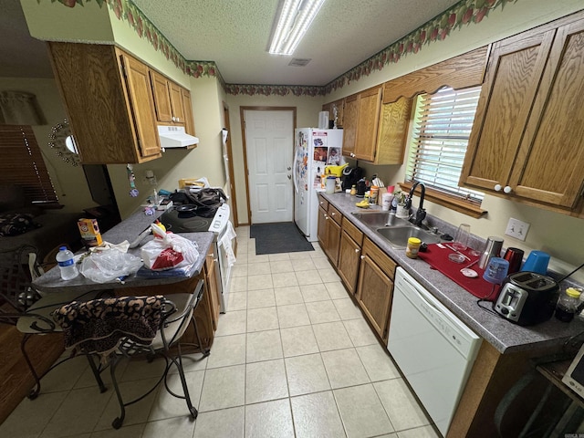 kitchen featuring range hood, white appliances, a sink, brown cabinets, and a textured ceiling