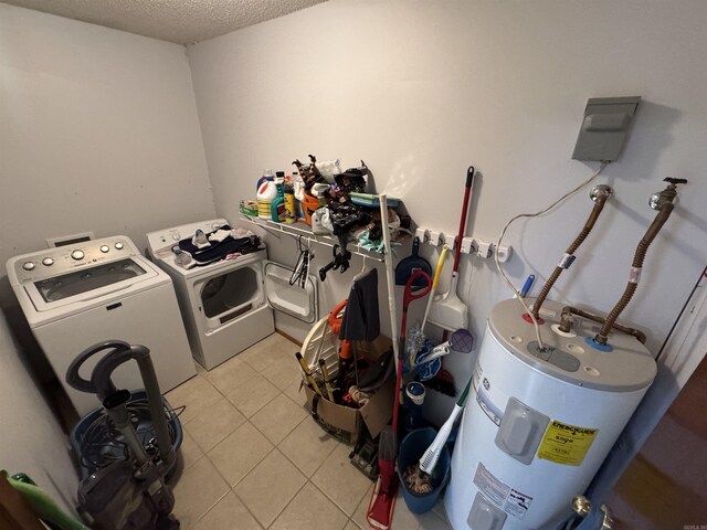 laundry area with washing machine and clothes dryer, electric water heater, light tile patterned floors, and a textured ceiling